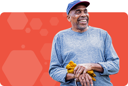 Man smiling and holding work gloves with orange background