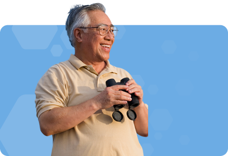 Man with glasses holding binoculars and smiling with light blue background